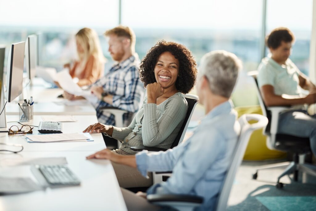 Happy Programmers Talking While Working In The Office